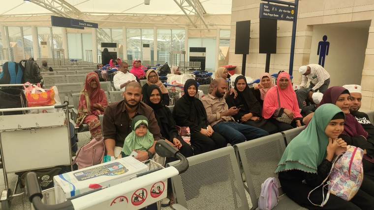 Families from the group waiting together with their bags in an airport departure hall.