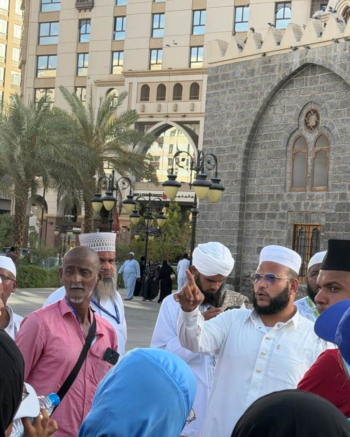 Pilgrims from the group standing and listening to the guide outside the Prophet&rsquo;s Mosque in Madinah.