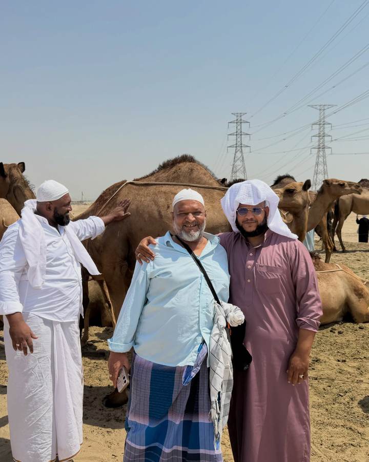 Three pilgrims from the group at a camel farm on the ziyarat route outside the city.